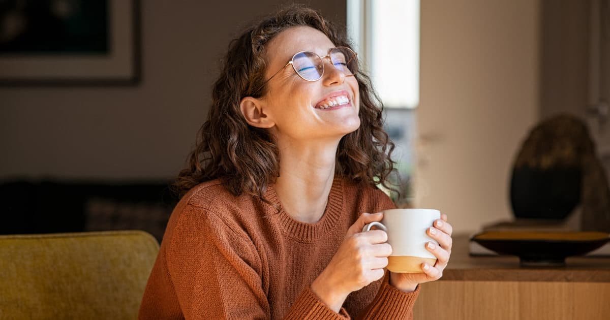 γυναίκα πίνει τον καφέ της και χαμογελά ανακουφισμένη
