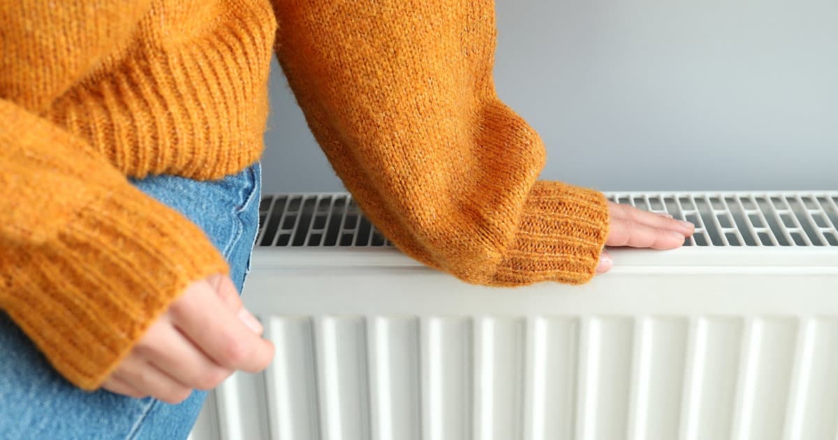 γυναικα ακουμπαει με το χερι της ενα καλοριφερ